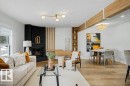 Corner fireplace with a black stone surround and hearth, wood-finish flooring, exposed ceiling beams, built-in shelving, and a modern dining light fixture - 49 Galloway Drive, Sherwood Park, AB  - Indoor Photo Showing Living Room With Fireplace 