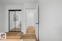Bright hallway featuring wood-finish flooring, white walls, and a recessed light fixture - 