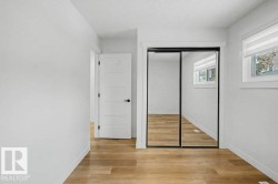 Bedroom featuring wood-finish flooring, crisp white walls, and a window with blinds - 