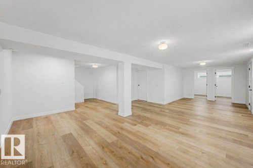 Spacious open-plan room featuring wood-finish flooring, white walls, and recessed lighting - 49 Galloway Drive, Sherwood Park, AB - Indoor Photo Showing Other Room