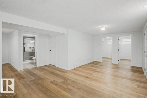 Expansive interior space featuring wood-finish flooring, white walls, and multiple doorways - 49 Galloway Drive, Sherwood Park, AB - Indoor Photo Showing Other Room