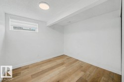 Bright room featuring white walls, wood-finish flooring, a contemporary flush-mount ceiling light, white baseboards, and a window with a horizontal blind - 
