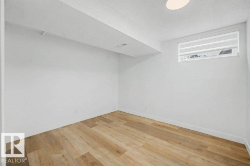 Bright room featuring light wood-finish flooring, white walls, and a single window with blinds - 49 Galloway Drive, Sherwood Park, AB - Indoor Photo Showing Other Room