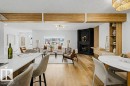 Open-concept living space featuring wood-finish flooring, a contemporary black fireplace, built-in wooden shelving, and a kitchen island with a white countertop - 49 Galloway Drive, Sherwood Park, AB  - Indoor Photo Showing Dining Room With Fireplace 