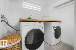 Dedicated laundry area featuring a wood-finish countertop, tiled flooring, and a wall-mounted drying rack - 