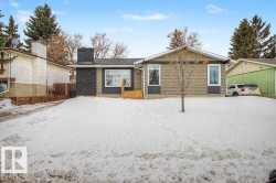 Ranch-style exterior with a dark stone-look chimney, light brown siding, and white trim windows - 