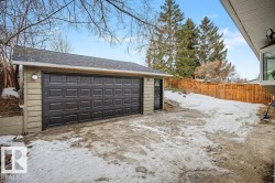 Detached garage with a dark panel-style overhead door, a separate entry door, and horizontal siding - 