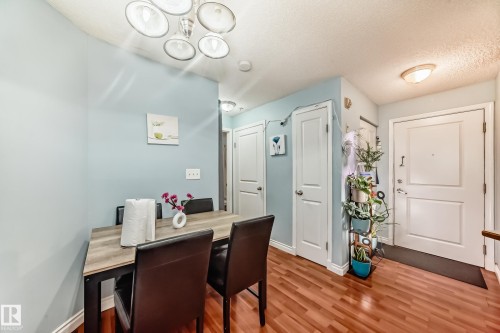 Hardwood-finish flooring in an interior space featuring light blue wall paint and white trim - 108 10535 122 Street, Edmonton, AB 