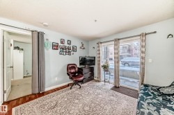 Living area featuring wood-finish flooring, light blue wall paint, and a sliding glass door leading to an outdoor patio - 