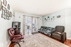 Living area featuring wood-finish flooring, light-colored walls, and a sliding glass door providing exterior access - 