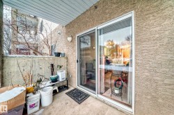 Private balcony featuring textured stucco exterior, concrete half-wall, and sliding glass door access - 