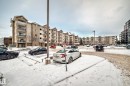 Multi-story residential building featuring light-colored brick and stucco facade, individual balconies with metal railings, and a ground-level entrance - 108 10535 122 Street, Edmonton, AB 