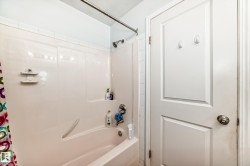 Bathroom featuring a tub/shower combination with a built-in ledge, white tile surround, and a brushed nickel shower head - 