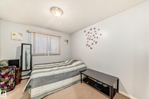 Neutral wall colors with textured ceiling, featuring a window with vertical blinds, and a flush-mount ceiling light fixture - 108 10535 122 Street, Edmonton, AB 