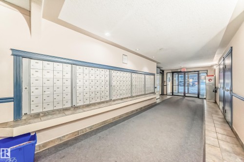 Building entryway featuring a wall of individual mailboxes, recessed lighting, and a glass-paneled entry door - 108 10535 122 Street, Edmonton, AB 