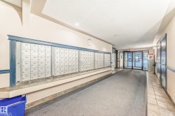 Building entryway featuring a wall of individual mailboxes, recessed lighting, and a glass-paneled entry door - 