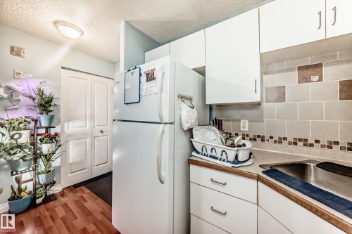 Kitchen area featuring light wood-finish flooring and white cabinetry - 108 10535 122 Street, Edmonton, AB 