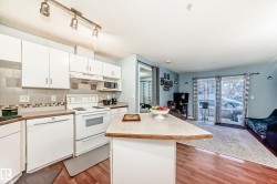 Open-concept living area featuring wood-finish flooring, white cabinetry, a tile backsplash, and a breakfast bar - 