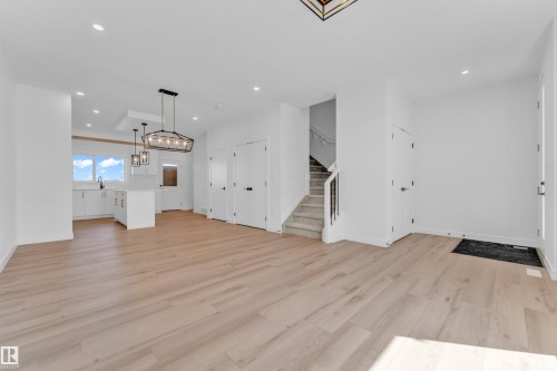 Open-concept living space with light wood-finish flooring, recessed lighting, and a modern kitchen - 175 Graybriar Drive, Stony Plain, AB 
