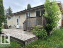 Rear facade featuring a wooden deck with railing, stucco exterior, and multiple windows - 5316 107 Street, Edmonton, AB 