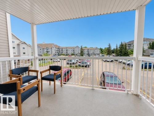 Private balcony featuring a textured concrete surface, white railing, and a slatted ceiling - 218 5065 31 Avenue, Edmonton, AB 