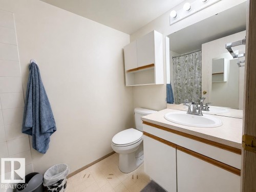 Bathroom vanity with a white integrated sink, chrome faucet, and a large mirror - 218 5065 31 Avenue, Edmonton, AB 