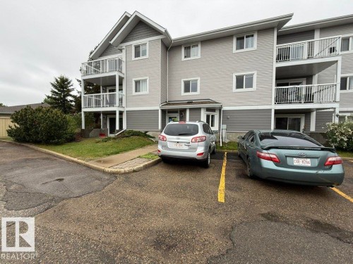 Multi-story building featuring light grey siding, white window frames, and private balconies with white railings - 218 5065 31 Avenue, Edmonton, AB 