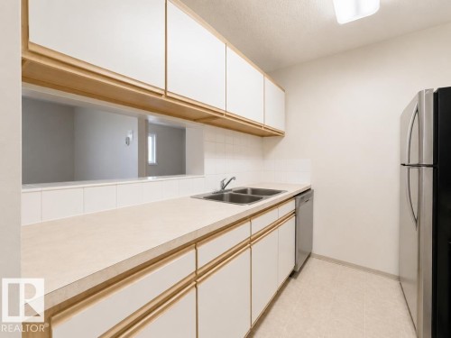 Kitchen featuring light-toned countertops, white subway tile backsplash, and wood-finish cabinetry - 218 5065 31 Avenue, Edmonton, AB 