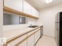Kitchen featuring light-toned countertops, white subway tile backsplash, and wood-finish cabinetry - 218 5065 31 Avenue, Edmonton, AB 