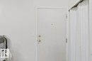 White interior door with brass hardware and a peephole, framed by white trim - 218 5065 31 Avenue, Edmonton, AB 