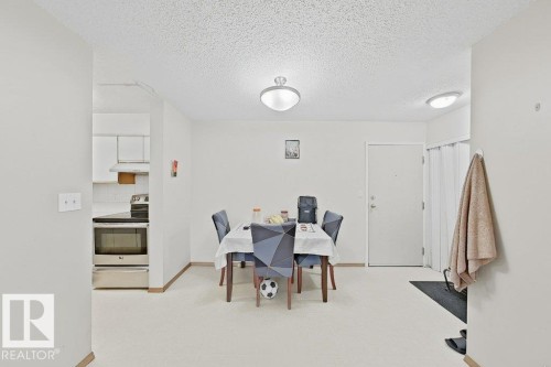 Dining area with recessed lighting, offering seamless access to the kitchen featuring a stainless steel range, white cabinetry, and a white tiled backsplash - 218 5065 31 Avenue, Edmonton, AB 