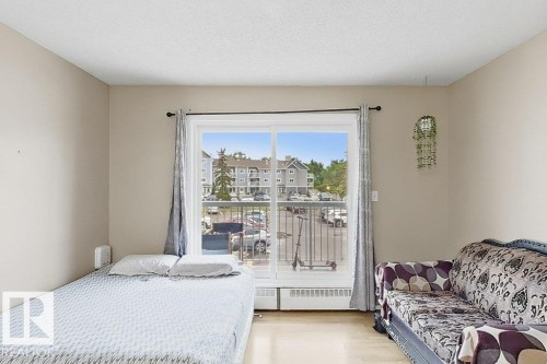 Bright room featuring neutral wall tones, light wood-finish flooring, and a large window with a white frame - 218 5065 31 Avenue, Edmonton, AB 