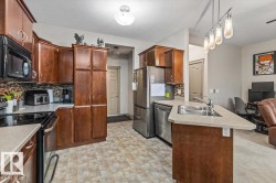 Kitchen featuring abundant wood-finish cabinetry, stainless steel appliances, a double basin sink, and mosaic tile backsplash - 