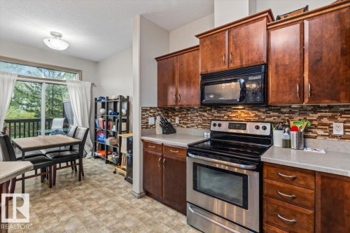 Kitchen featuring wood cabinetry, stainless steel range, and a mosaic tile backsplash - 229 41 Summerwood Boulevard, Sherwood Park, AB - Indoor Photo Showing Kitchen