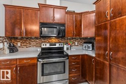 Kitchen featuring wood cabinetry, stainless steel range, built-in microwave, and a mosaic tile backsplash - 