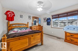Spacious room featuring a large window with horizontal blinds, light-colored carpeting, a partial accent wall with a geometric pattern, and a ceiling fan with integrated lighting - 