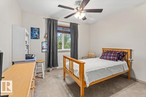 Carpeted room featuring a ceiling fan with integrated lighting, a window with horizontal blinds, and a built-in wall shelf - 229 41 Summerwood Boulevard, Sherwood Park, AB - Indoor Photo Showing Bedroom