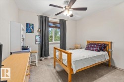 Carpeted room featuring a ceiling fan with integrated lighting, a window with horizontal blinds, and a built-in wall shelf - 