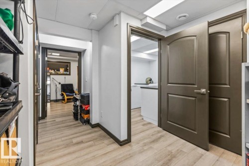 Interior hallway with wood-finish flooring, white walls, and dark trim - 229 41 Summerwood Boulevard, Sherwood Park, AB - Indoor Photo Showing Other Room