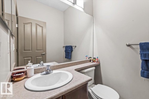 Bathroom featuring an integrated sink, laminate countertop, mirrored wall, and a toilet - 229 41 Summerwood Boulevard, Sherwood Park, AB - Indoor Photo Showing Bathroom