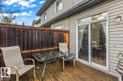 Outdoor deck space featuring wood-finish flooring, a dark wood privacy fence, and light-colored siding - 