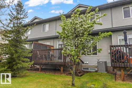 Rear exterior featuring light gray siding, multiple windows, and a dark wood-finish deck with privacy screening - 229 41 Summerwood Boulevard, Sherwood Park, AB - Outdoor With Deck Patio Veranda With Exterior