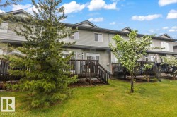 Rear exterior with a spacious wooden deck featuring a full-height privacy railing and stairs descending to a green lawn - 