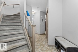 Carpeted staircase with light-toned wood newel post and balusters featuring metal spindles - 