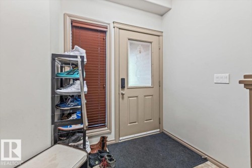 Entryway featuring a paneled door with decorative glass insert, a window with horizontal blinds, and light-toned wall finishes - 229 41 Summerwood Boulevard, Sherwood Park, AB - Indoor Photo Showing Other Room