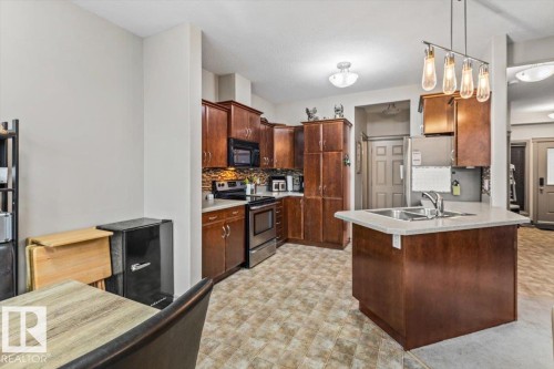 Kitchen featuring wood-finish cabinetry, stainless steel appliances, and a tiled backsplash - 229 41 Summerwood Boulevard, Sherwood Park, AB - Indoor Photo Showing Kitchen With Double Sink