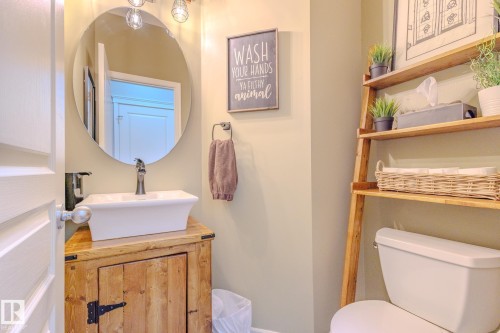 Compact bathroom featuring a white vessel sink set on a rustic wood-finish vanity with a black forged hinge - 7207 14A Avenue, Edmonton, AB - Indoor Photo Showing Bathroom