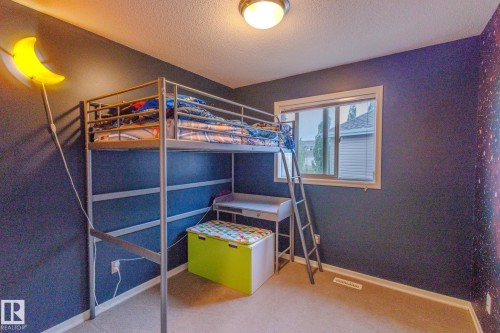 Windowed room with a full-height loft bed frame, neutral carpet flooring, and a flush-mount ceiling light fixture - 7207 14A Avenue, Edmonton, AB - Indoor