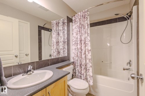 Bathroom featuring a built-in vanity with a dark speckled countertop, an integrated sink with a chrome faucet, and a large mirror extending to the ceiling - 7207 14A Avenue, Edmonton, AB - Indoor Photo Showing Bathroom