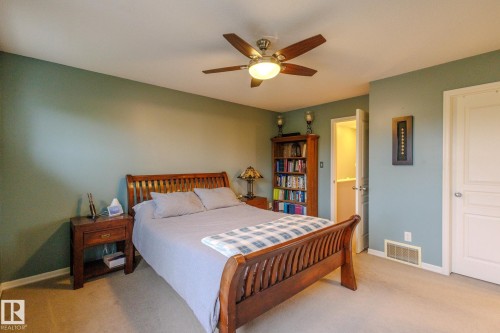 Spacious room featuring a ceiling fan with integrated lighting, soft green wall color, and light-toned carpet flooring - 7207 14A Avenue, Edmonton, AB - Indoor Photo Showing Bedroom